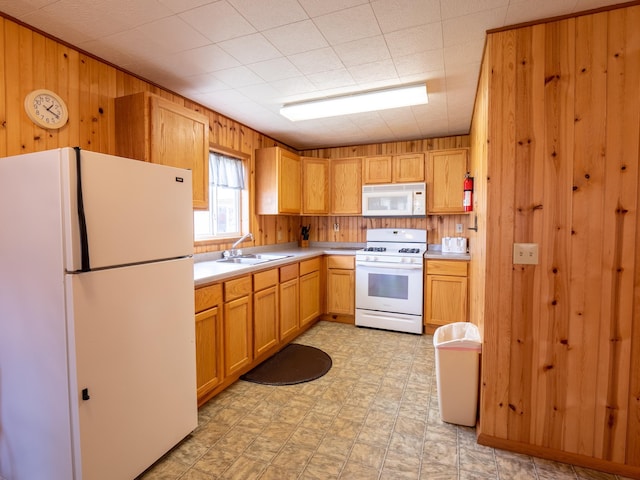 kitchen with wooden walls, sink, and white appliances