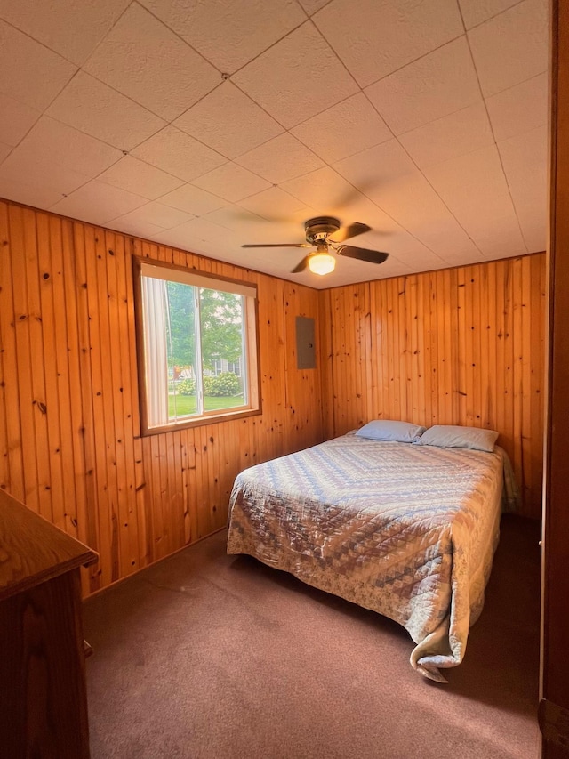 bedroom with ceiling fan, carpet, electric panel, and wooden walls