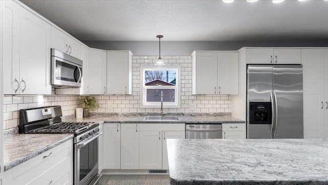 kitchen featuring sink, white cabinets, pendant lighting, and stainless steel appliances