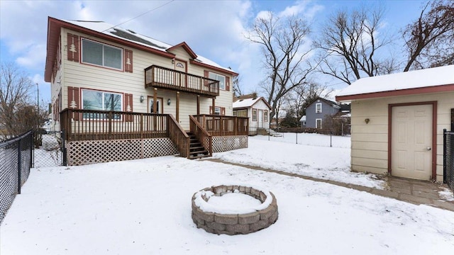 snow covered back of property featuring a fire pit, a wooden deck, and a balcony