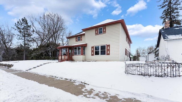 snow covered back of property with covered porch