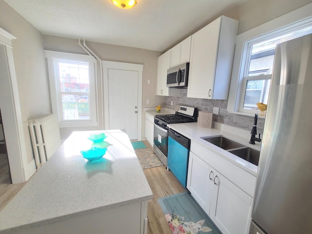 kitchen with sink, backsplash, white cabinetry, and appliances with stainless steel finishes