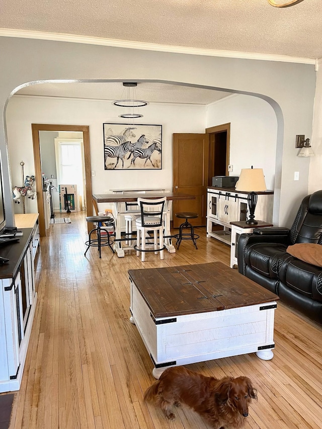 living room featuring crown molding, a textured ceiling, and light wood-type flooring