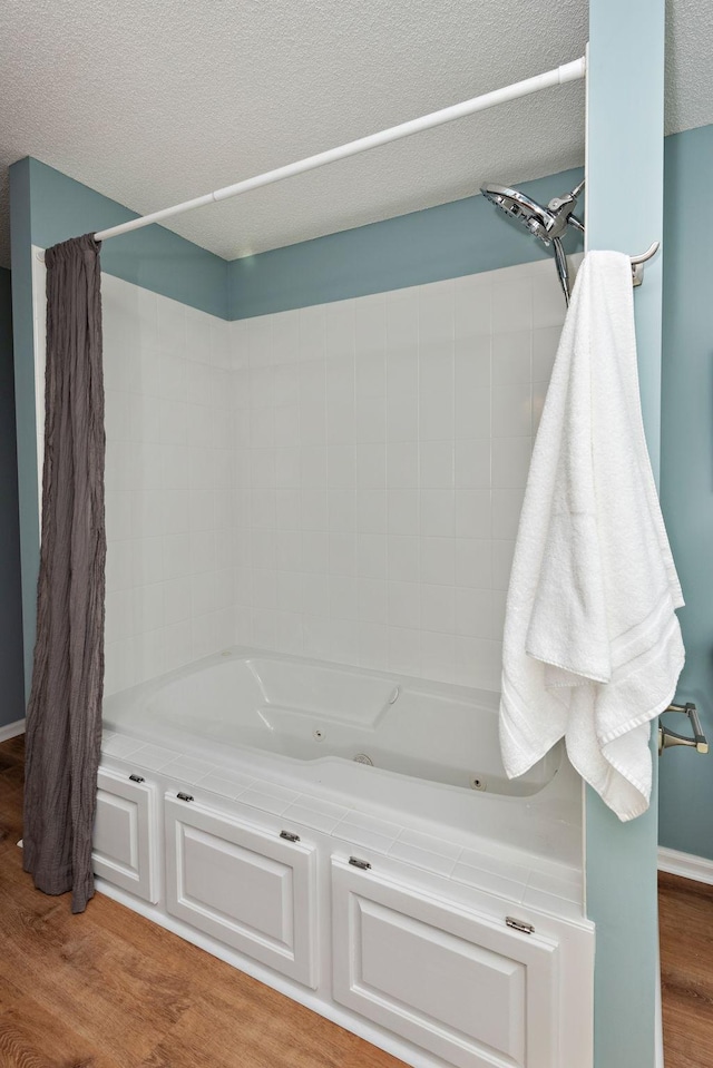 bathroom with shower / bathtub combination with curtain, hardwood / wood-style flooring, and a textured ceiling