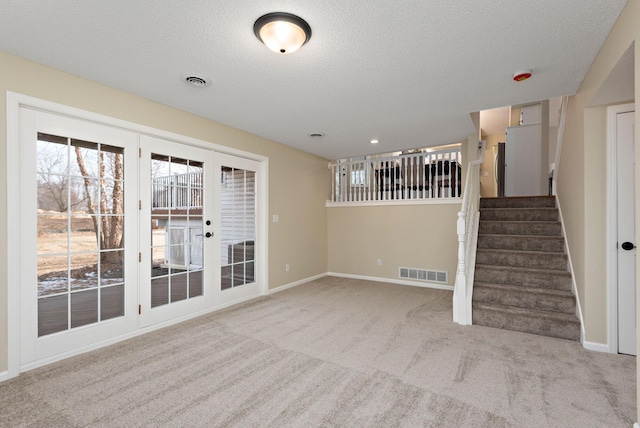 unfurnished living room with light colored carpet and a textured ceiling