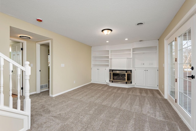 unfurnished living room with light colored carpet and a textured ceiling