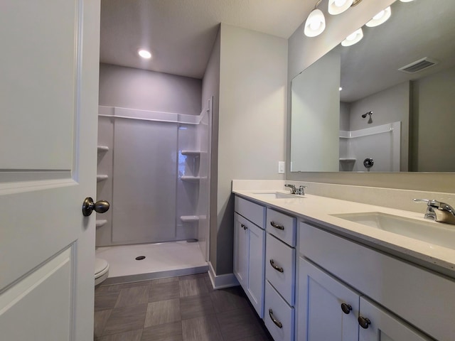 bathroom featuring vanity, walk in shower, and toilet