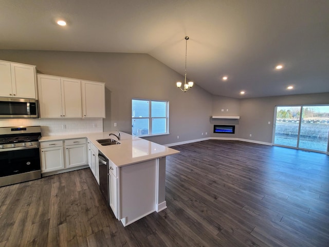 kitchen with kitchen peninsula, sink, white cabinets, decorative backsplash, and stainless steel appliances