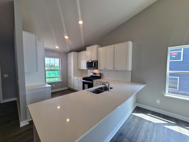 kitchen with kitchen peninsula, dark hardwood / wood-style flooring, sink, white cabinetry, and stainless steel appliances