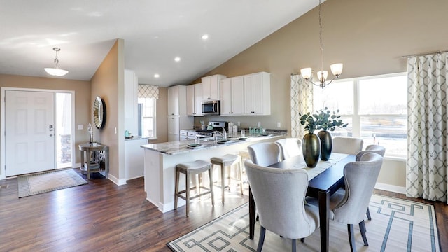 dining area with lofted ceiling, dark hardwood / wood-style floors, and a chandelier