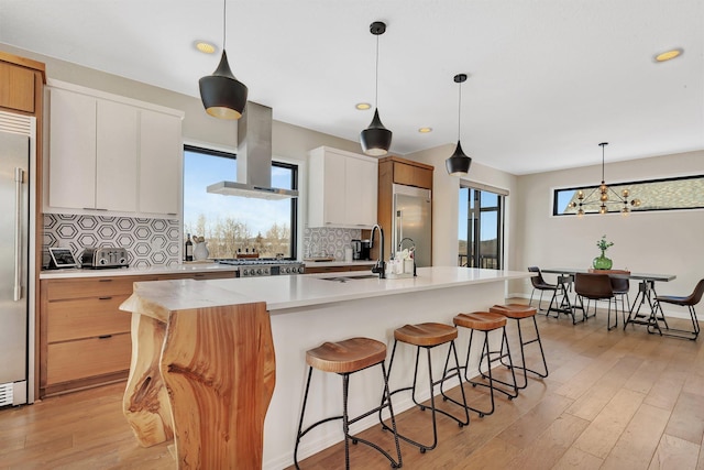 kitchen featuring island range hood, backsplash, white cabinets, and a kitchen island with sink