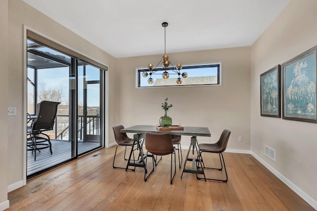 dining space featuring light wood-type flooring and a notable chandelier