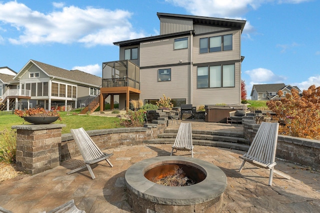 rear view of house featuring a hot tub, a fire pit, a sunroom, and a patio