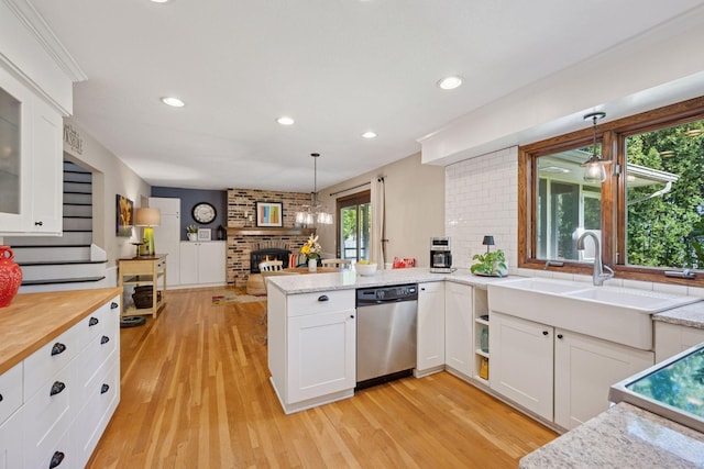 2500 Urbandale Ln N, Plymouth, MN 55447 - kitchen featuring stainless steel dishwasher, a fireplace, white cabinetry, a peninsula, and light wood-type flooring