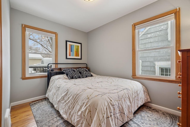 bedroom featuring multiple windows, wood finished floors, and baseboards