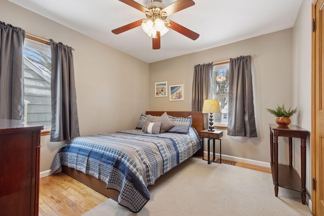 bedroom featuring light wood-style flooring, baseboards, and ceiling fan