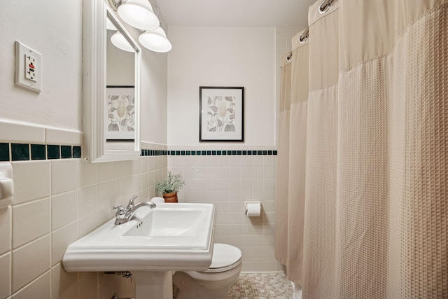 full bath with a sink, tile patterned flooring, curtained shower, tile walls, and toilet