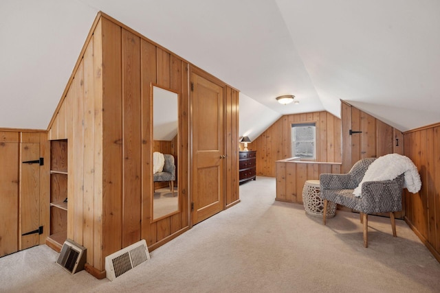 additional living space with visible vents, light carpet, wooden walls, and lofted ceiling