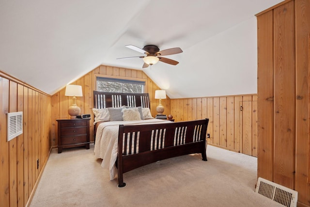 bedroom featuring visible vents, wooden walls, ceiling fan, carpet, and vaulted ceiling