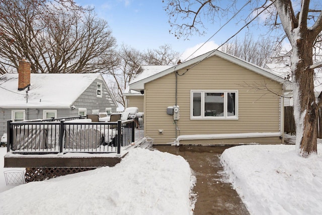 snow covered rear of property with a wooden deck