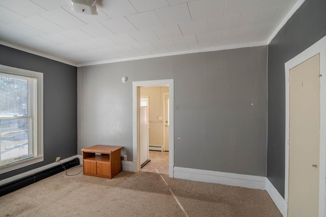 carpeted empty room with a baseboard heating unit and crown molding