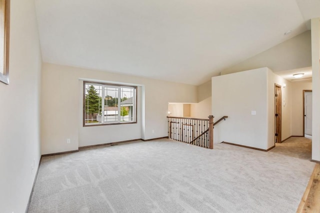 carpeted spare room with vaulted ceiling