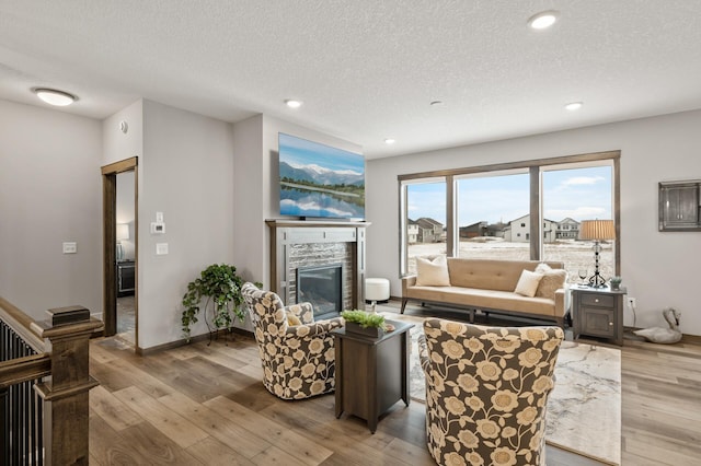 9971 14th Cir NE, Saint Michael, MN 55376 - living area with wood-type flooring, a stone fireplace, a textured ceiling, recessed lighting, and baseboards