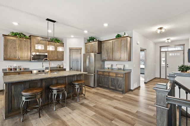 9971 14th Cir NE, Saint Michael, MN 55376 - kitchen featuring appliances with stainless steel finishes, light wood-type flooring, a breakfast bar area, a sink, and recessed lighting