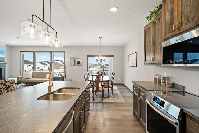 9971 14th Cir NE, Saint Michael, MN 55376 - kitchen featuring stainless steel appliances, a sink, wood finished floors, a textured ceiling, and hanging light fixtures