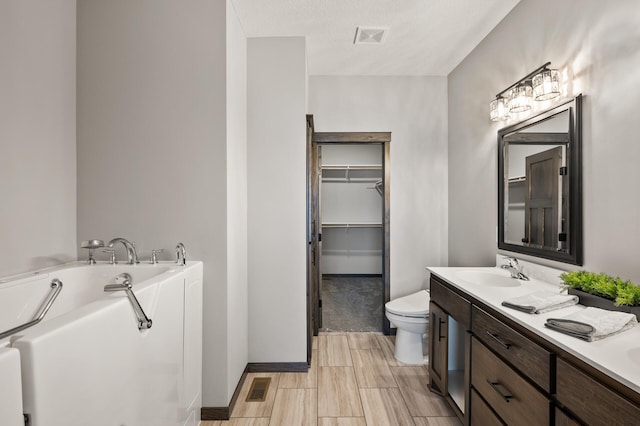 9971 14th Cir NE, Saint Michael, MN 55376 - bathroom featuring a bath, double vanity, toilet, a walk in closet, and baseboards