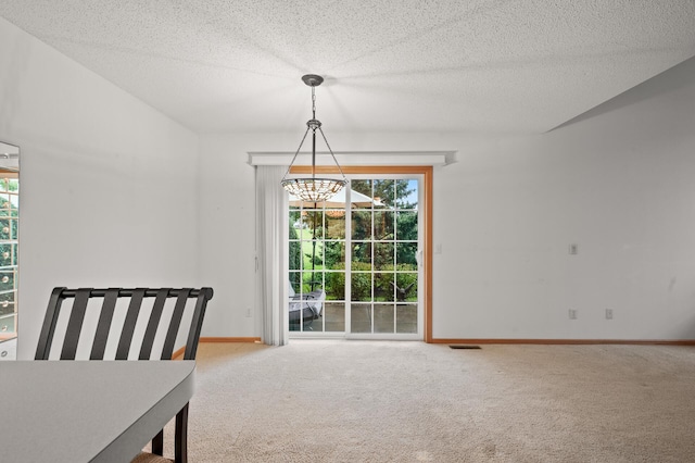 unfurnished dining area featuring a textured ceiling, a chandelier, and carpet floors