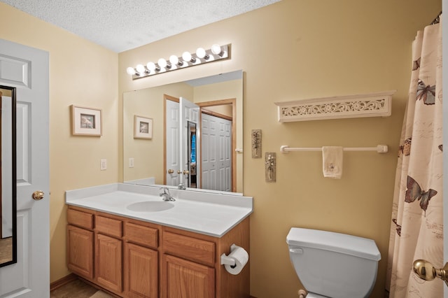 bathroom featuring a textured ceiling, toilet, and vanity