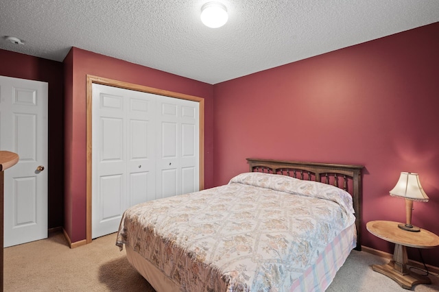 bedroom with a closet, light colored carpet, and a textured ceiling