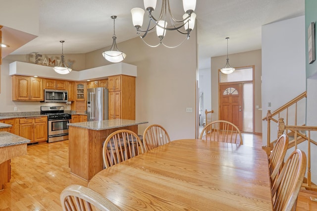 dining room with a towering ceiling, light hardwood / wood-style flooring, and a chandelier