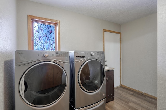 laundry area featuring cabinets, separate washer and dryer, a textured ceiling, and light hardwood / wood-style floors