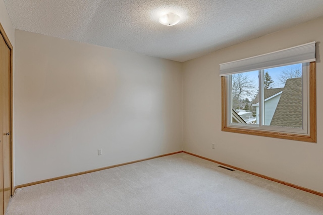 spare room with carpet and a textured ceiling