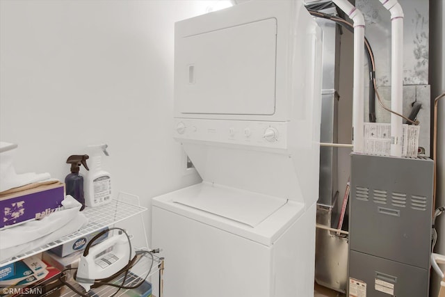 laundry area with heating unit and stacked washer and clothes dryer