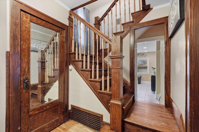 stairway featuring wood-type flooring and ornamental molding