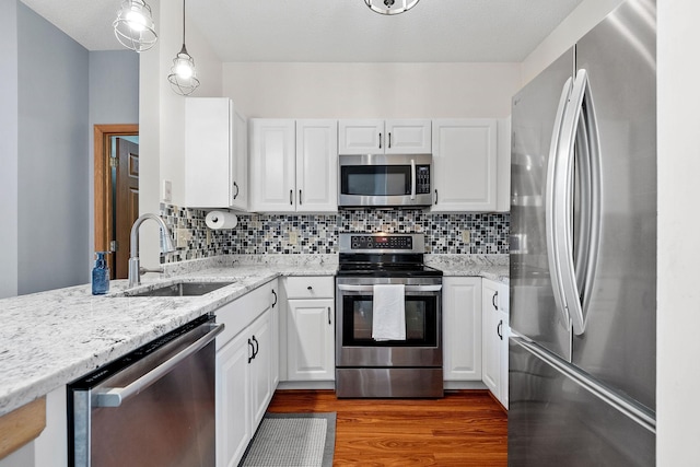 kitchen featuring white cabinetry, stainless steel appliances, sink, and hanging light fixtures