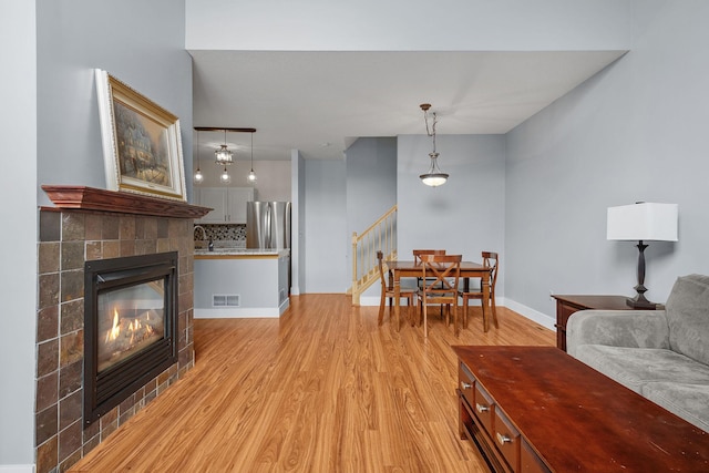 living room with a tile fireplace and light wood-type flooring