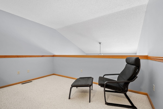 sitting room featuring lofted ceiling, light carpet, and a textured ceiling