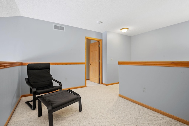 sitting room with lofted ceiling, light carpet, and a textured ceiling