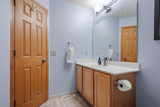 bathroom with hardwood / wood-style flooring, vanity, and a textured ceiling