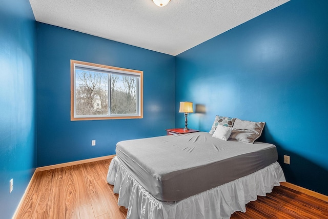 bedroom with a textured ceiling and light hardwood / wood-style flooring