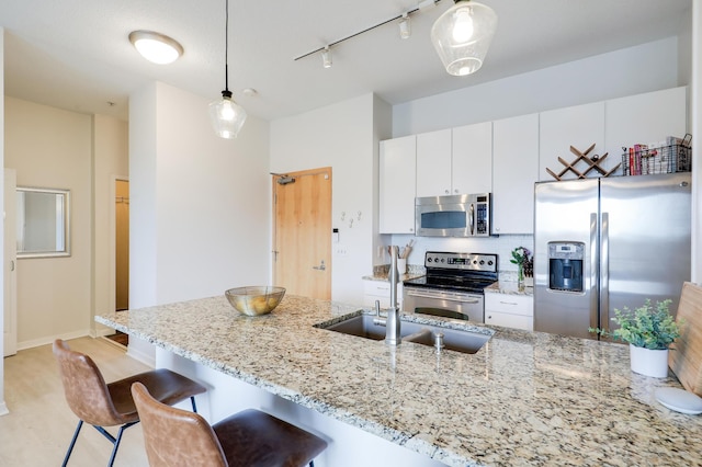 kitchen with sink, white cabinets, hanging light fixtures, and stainless steel appliances