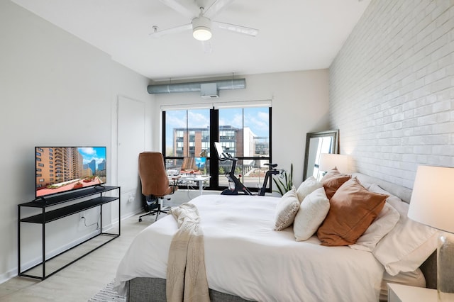 bedroom with ceiling fan, brick wall, and light wood-type flooring