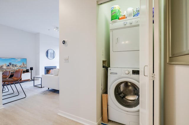 laundry area with light wood-type flooring and stacked washer and dryer