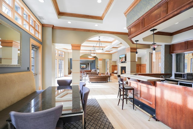 dining room featuring coffered ceiling, sink, a raised ceiling, light hardwood / wood-style flooring, and ornamental molding