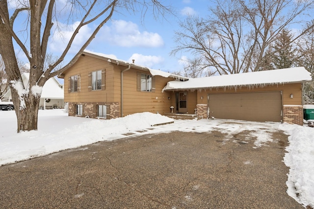 split level home with a garage, brick siding, and driveway