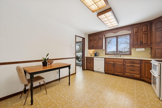 kitchen featuring white appliances, light floors, baseboards, a sink, and light countertops